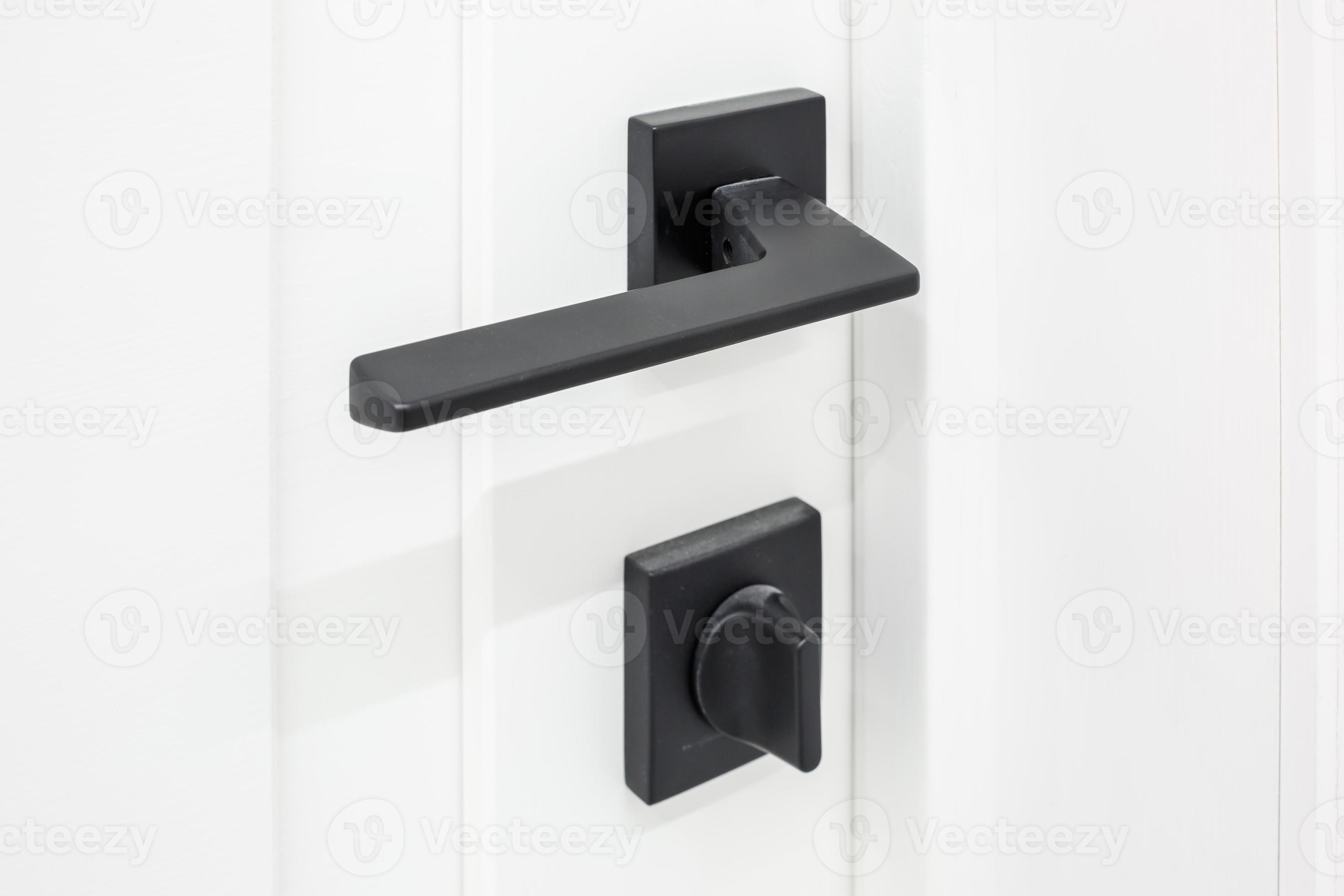 Modern black door handle on white wooden door in interior. Knob closeup elements. Door handle