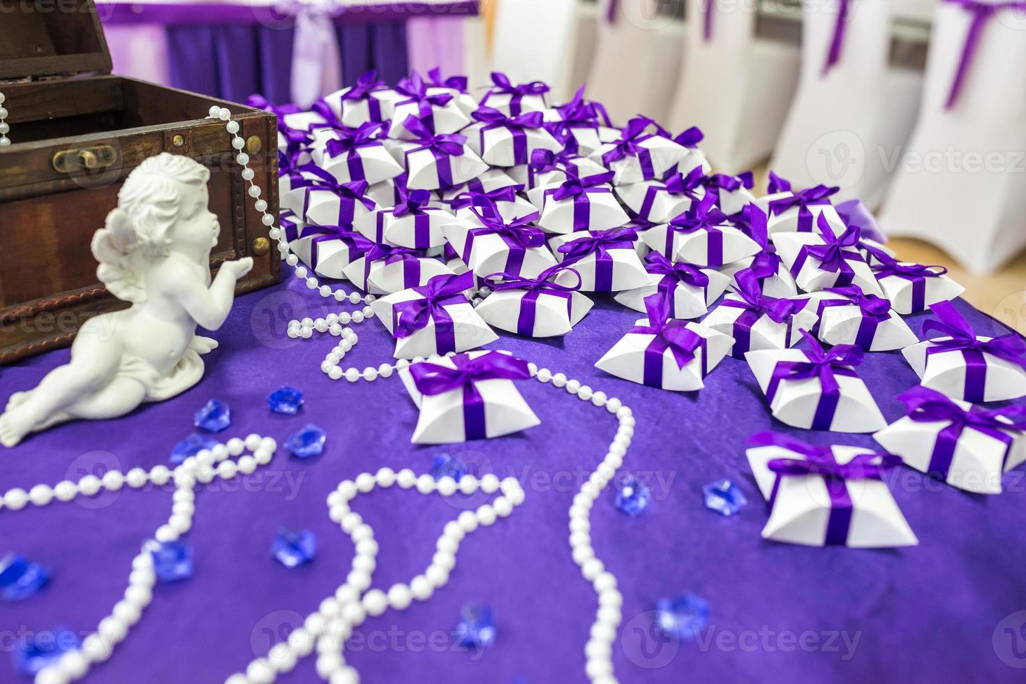 ceramic angel on the table with a violet tablecloth and small gifts for guests from the newlyweds photo
