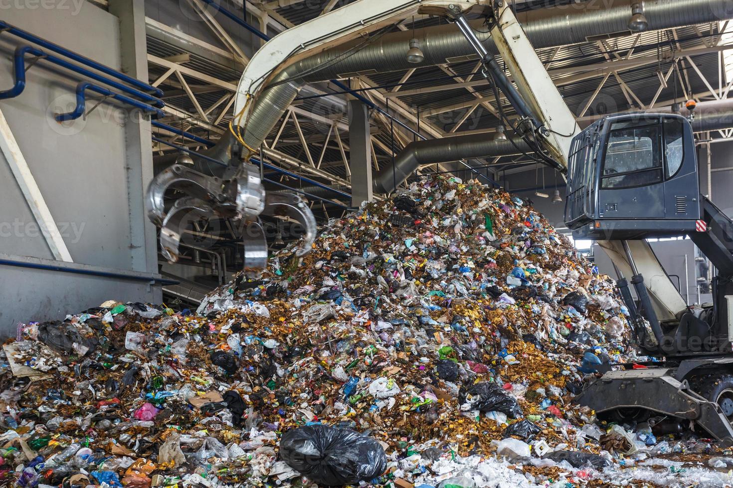 Excavator on primary sorting of garbage at waste processing plant. Separate garbage collection. Recycling and storage of waste for further disposal. Business for sorting and processing of waste. photo