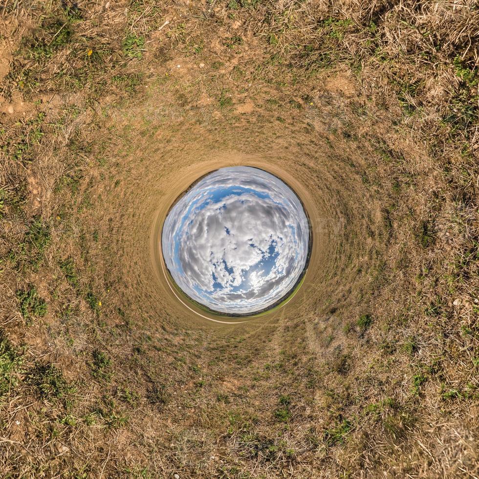 Little planet transformation of spherical panorama 360 degrees. Spherical abstract aerial view in field with awesome beautiful clouds. Curvature of space. photo