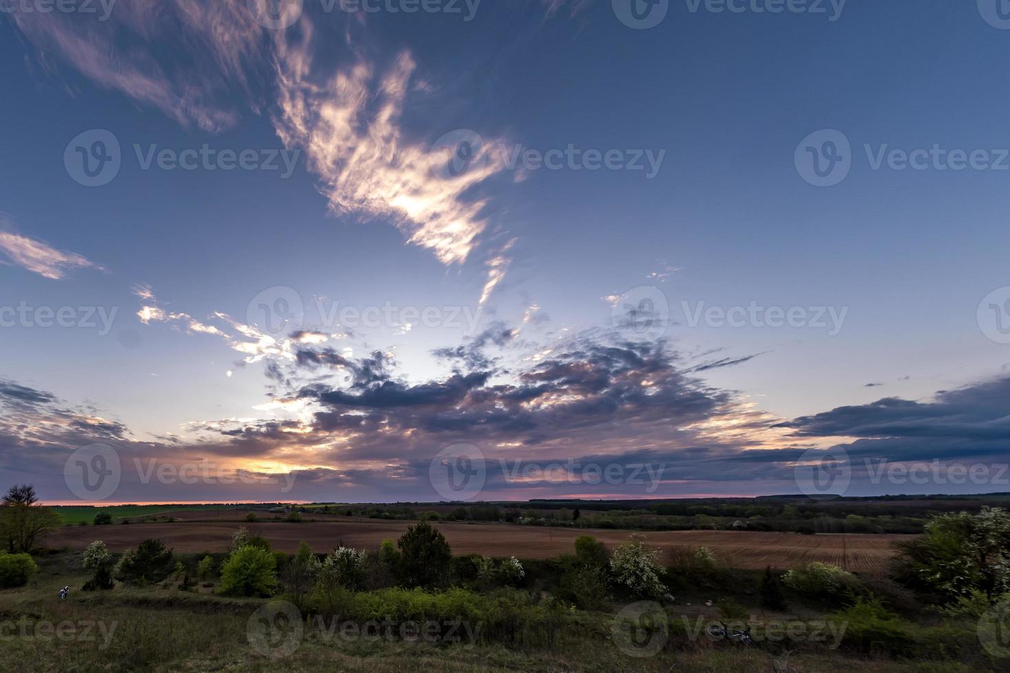 fondo de cielo rojo azul con nubes onduladas rizadas esponjosas por la noche con sol poniente. buen clima ventoso foto