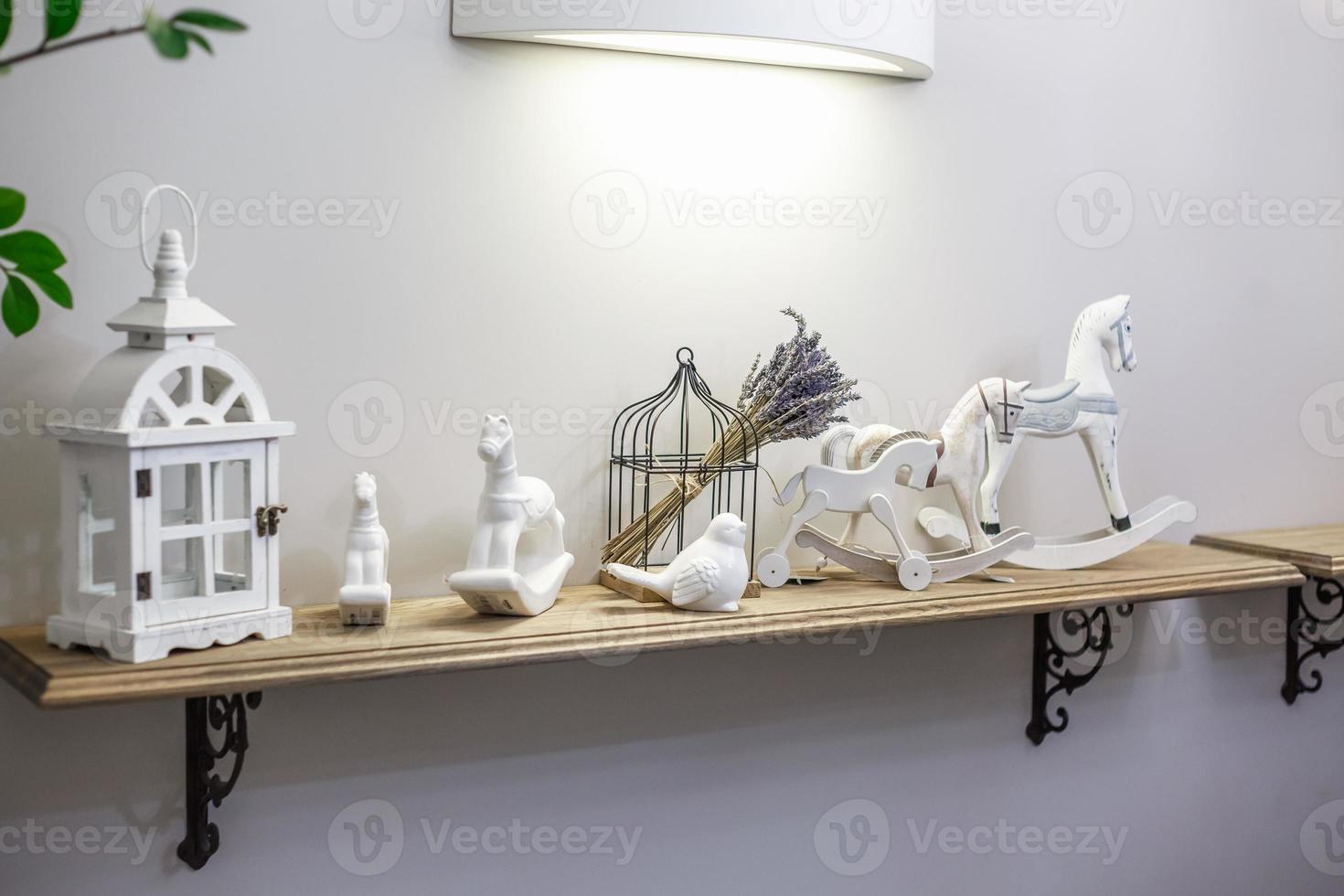 interior decoration toys. White decorative wooden latern lights and ceramic horses in expensive interior photo