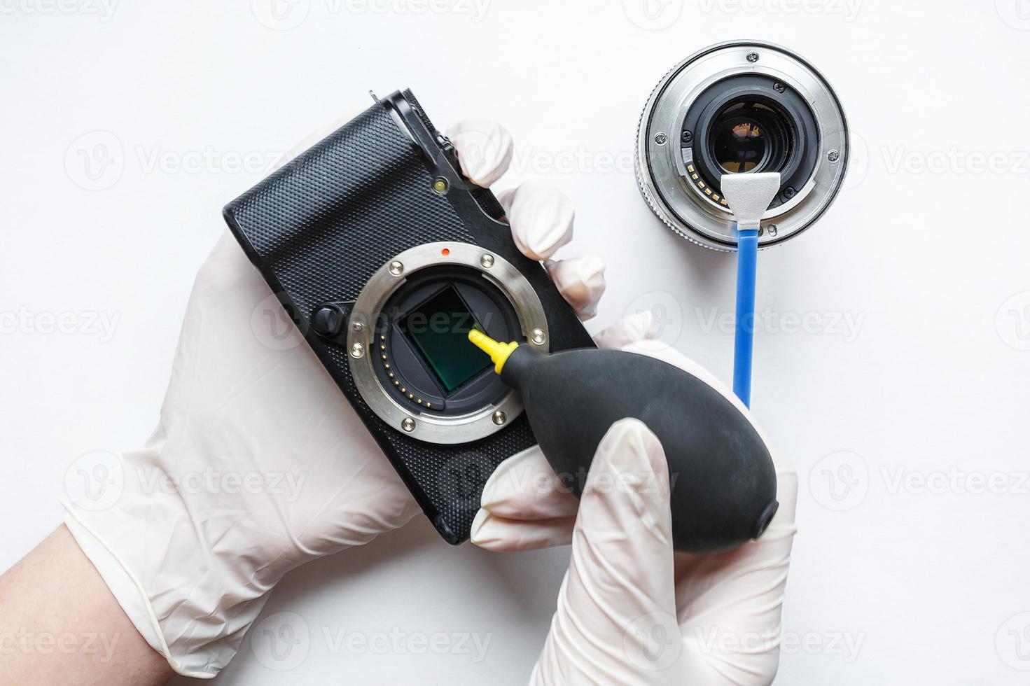 Close-up of mirrorless digital APS-C dirty camera matrix sensor cleaning and maintenance with swab, photographer cleaning photocamera on white background photo