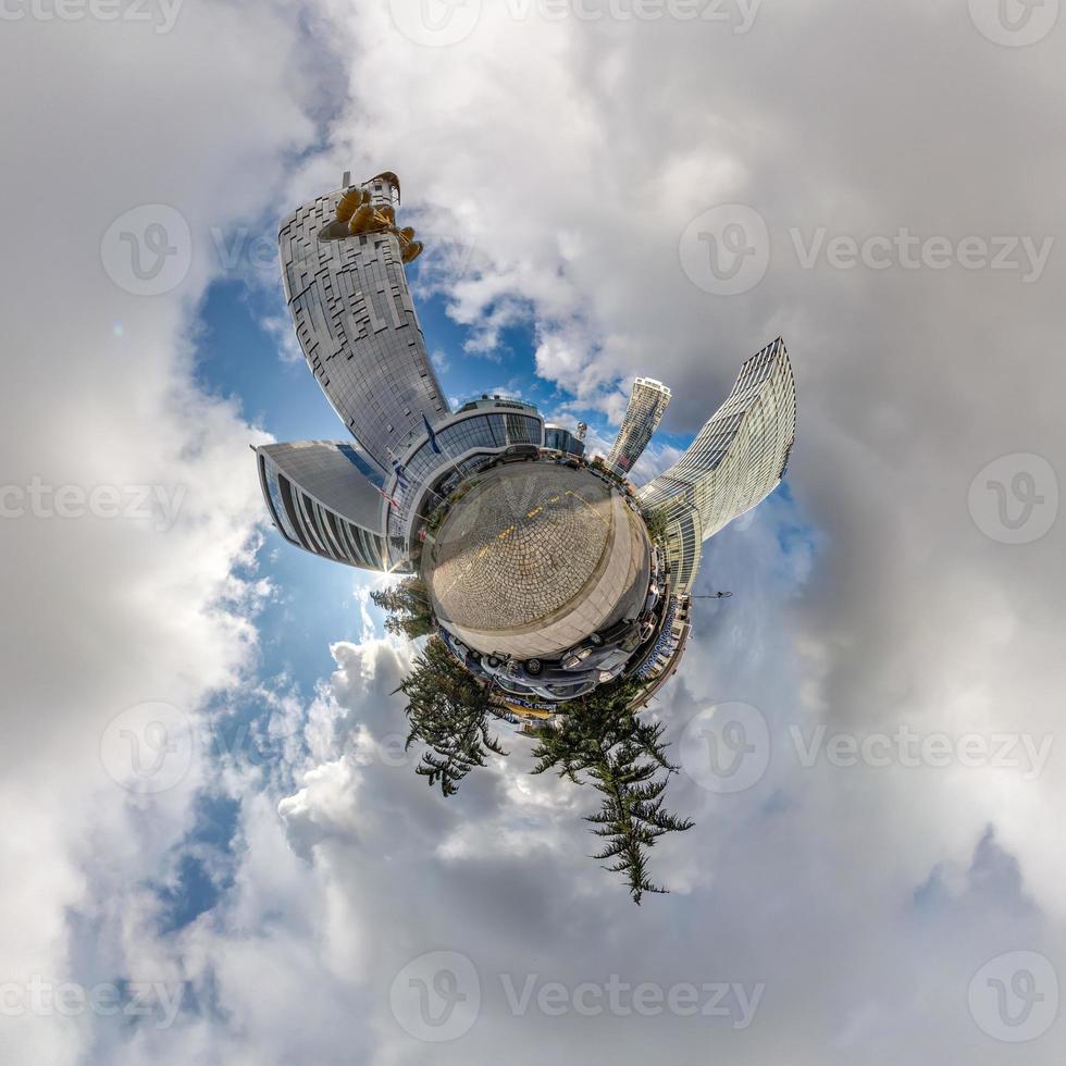 tiny planet in blue sky with clouds in city center near modern skyscrapers or office buildings. Transformation of spherical 360 panorama in abstract aerial view. photo