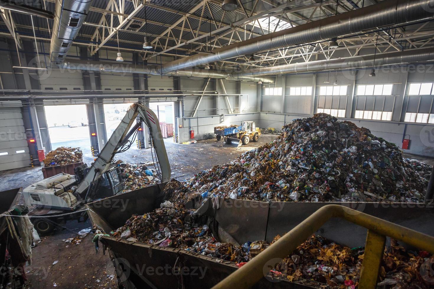 Excavator on primary sorting of garbage at waste processing plant. Separate garbage collection. Recycling and storage of waste for further disposal. Business for sorting and processing of waste. photo