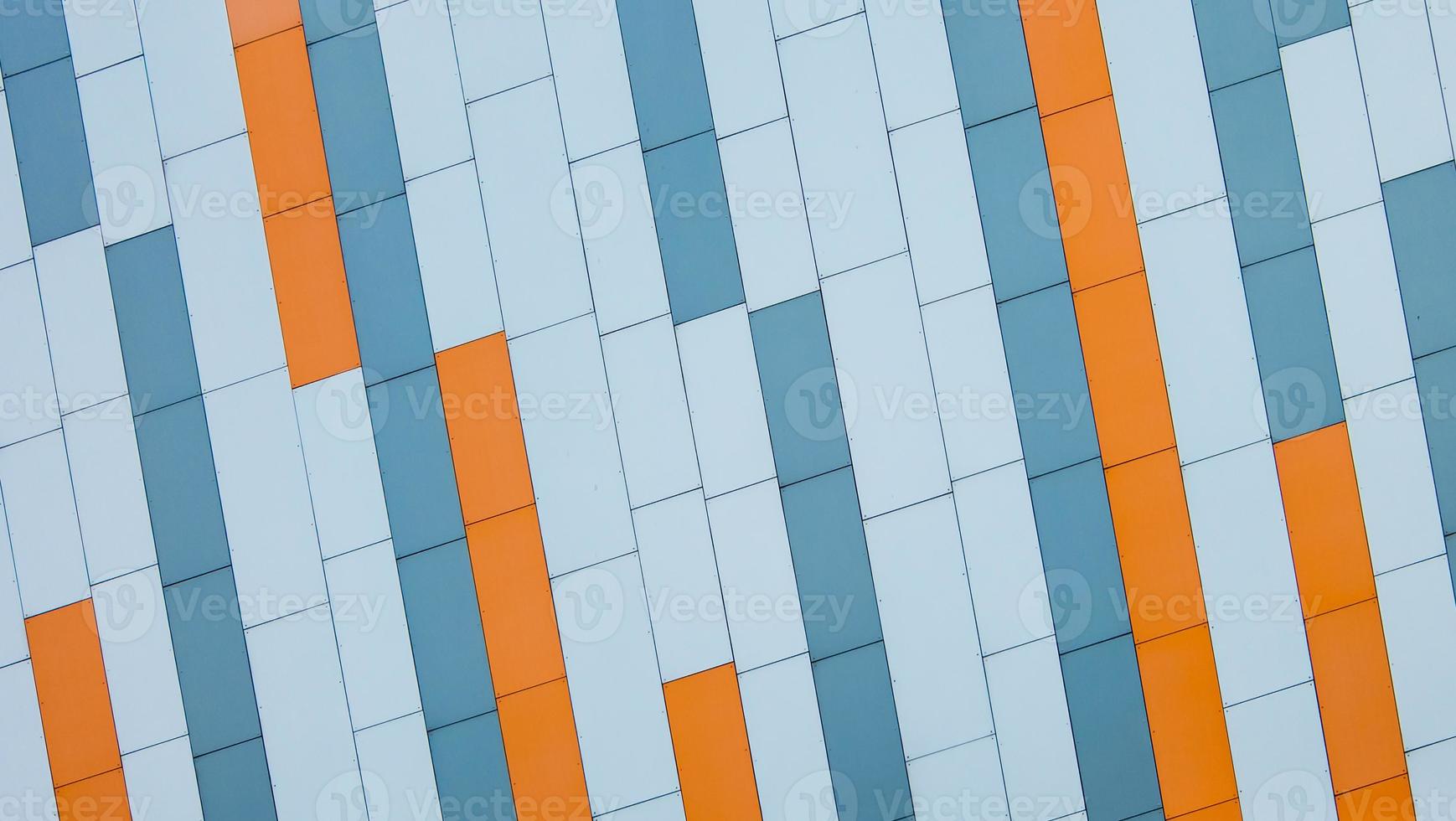 Facade of modern building faced with sloping orange blue and gray sandwich colorful panels. Architectural background. photo
