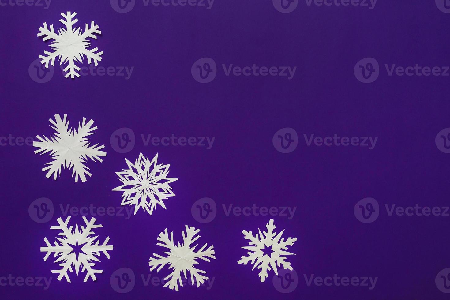 White paper snowflakes different shapes and sizes on violet background. Top view. photo