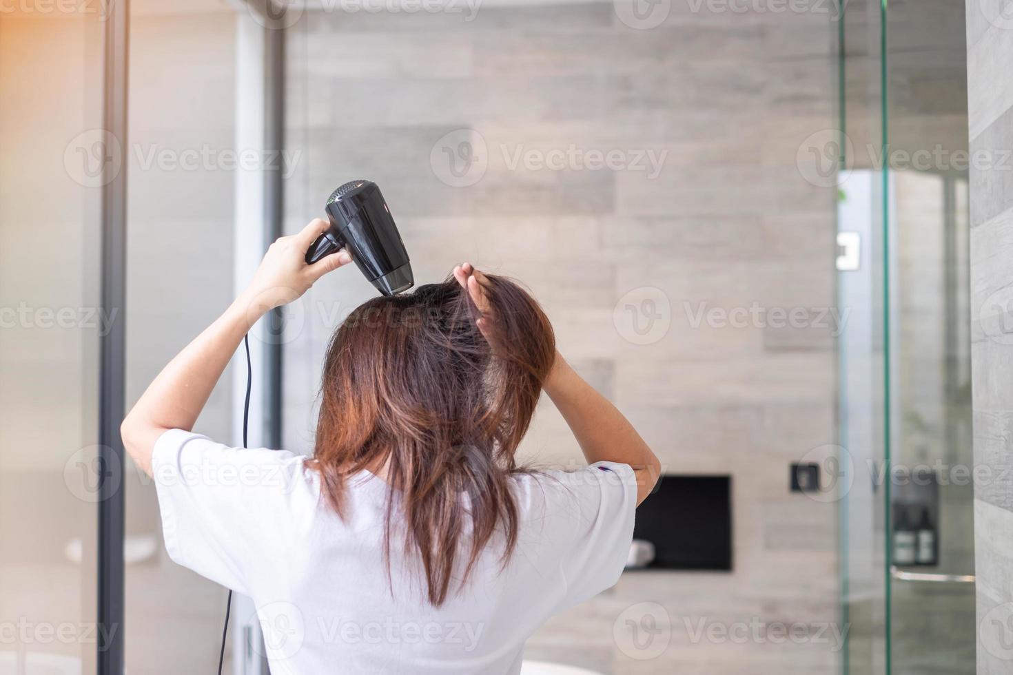 mujer joven que usa secador de pelo en casa o en el hotel. peinados y conceptos de estilo de vida foto