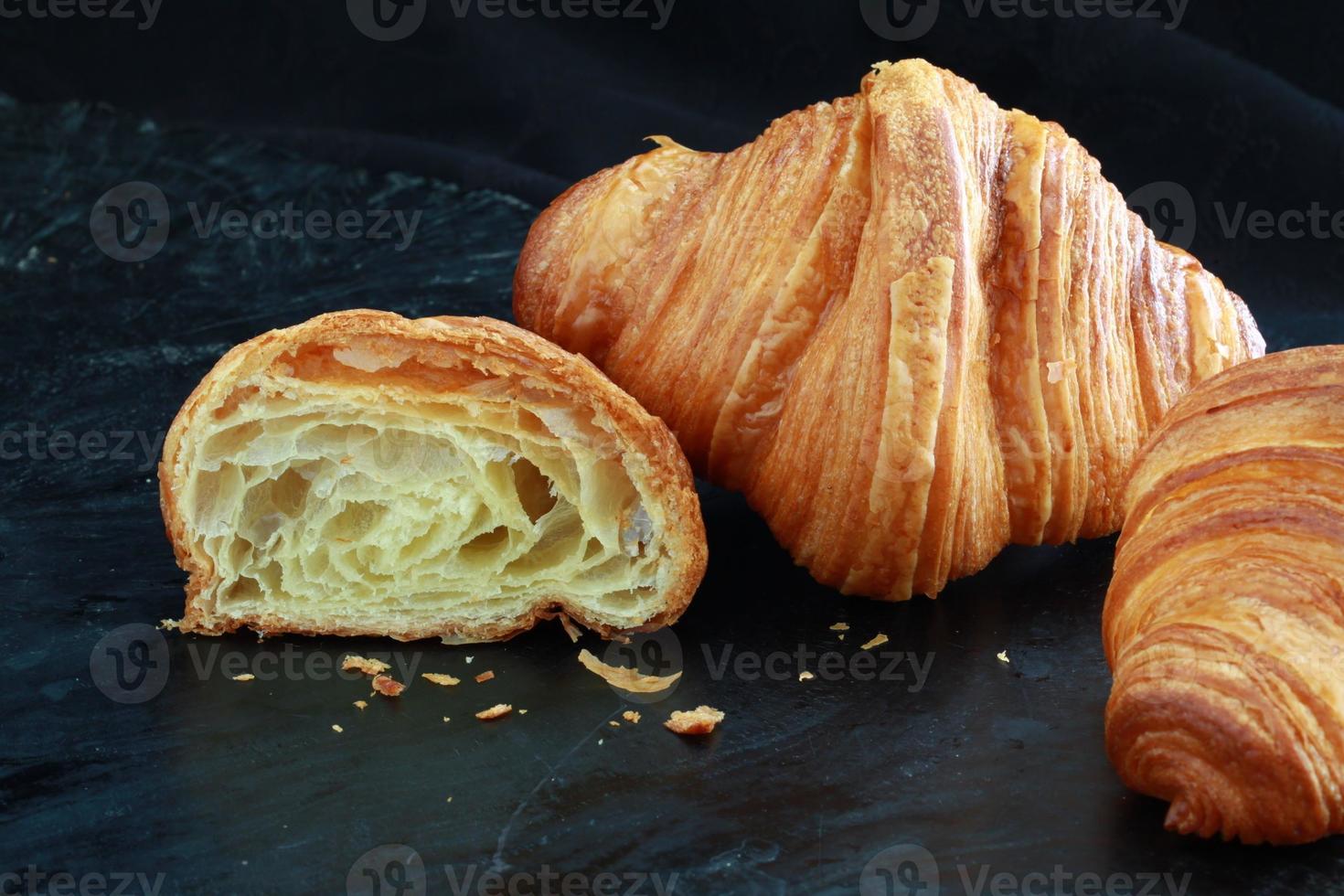 French croissant, halved, look at the texture, buttery fresh on dark background. Shoot close up photo