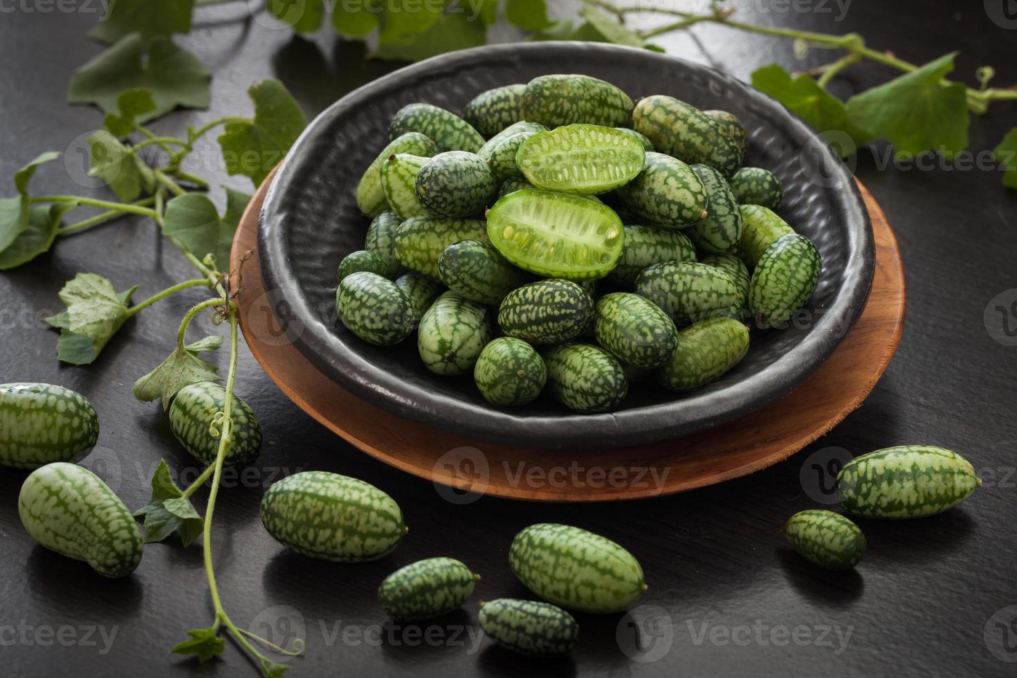 Cucamelon also known as Melothria scabra, Mexican sour cucumber gherkin, Freshly picked. Close up in a ceramic plate, Dark wooden background photo