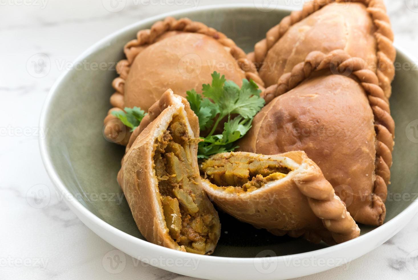 Malaysian deep fried curry puff or epok-epok, vegetarian food, isolated on white background on a plate, is Asian traditional snacks that has crispy skins. Close up food photo