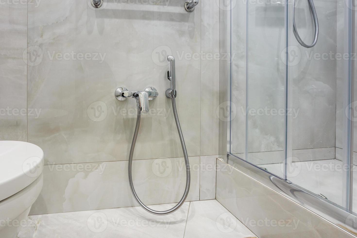 details of corner shower cabin with wall mount shower attachment and water tap sink with faucet in expensive bathroom photo