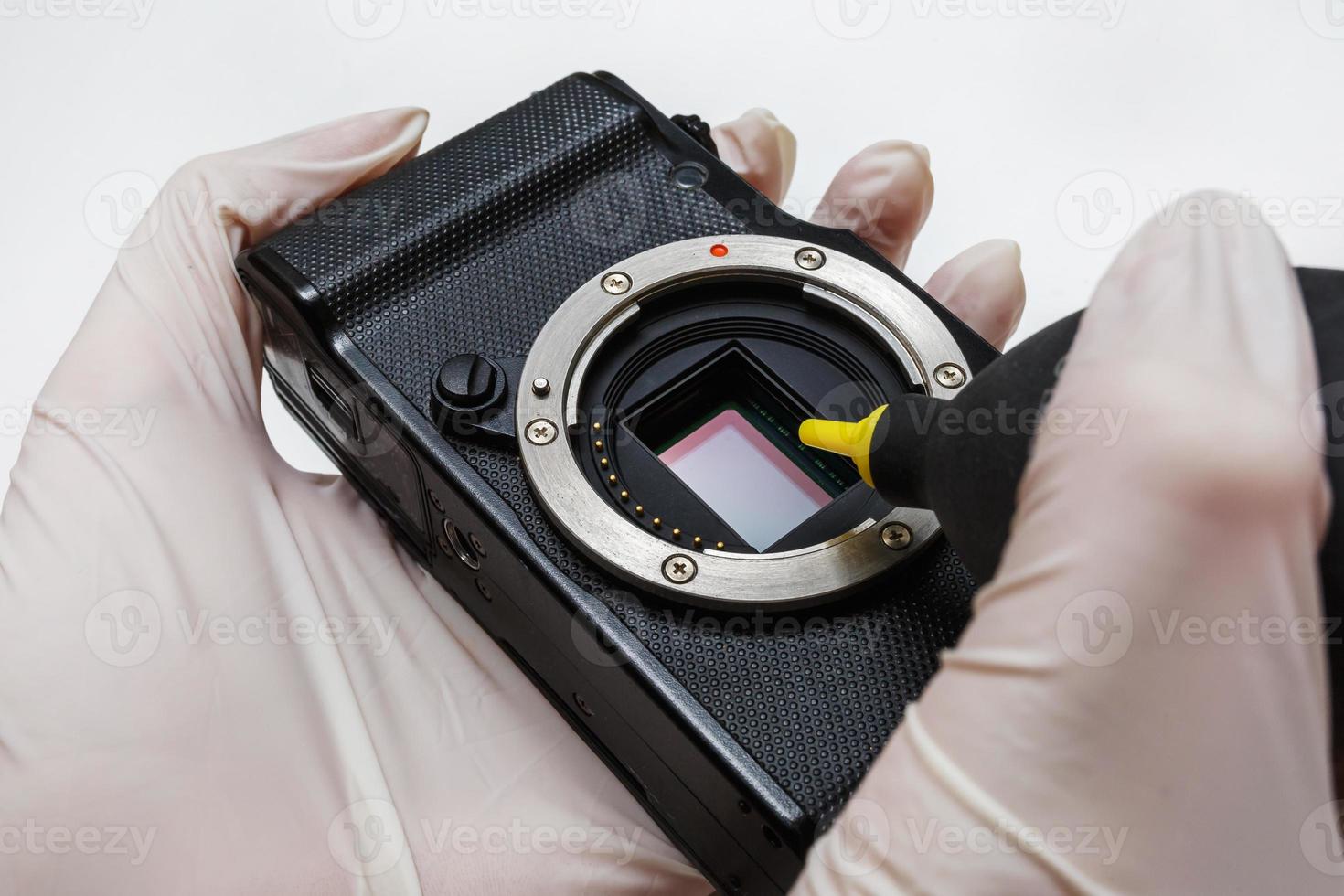 Close-up of mirrorless digital APS-C dirty camera matrix sensor cleaning and maintenance with swab, photographer cleaning photocamera on white background photo