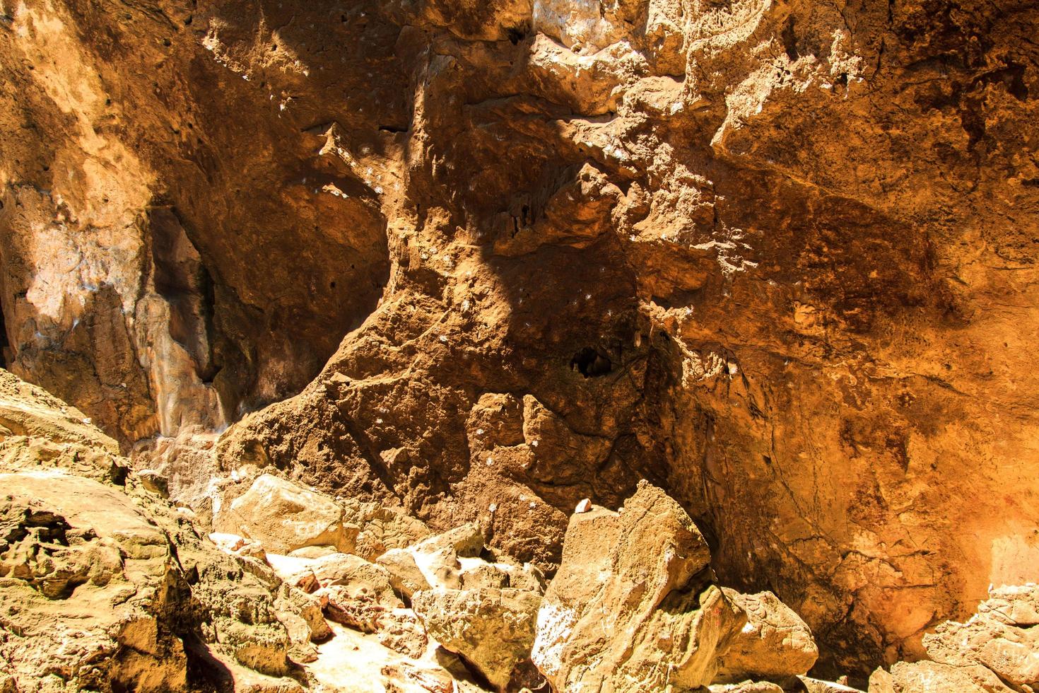 piedra caliza de granito en la cueva, pero la luz del sol brilla intensamente, mostrando las curvas y formas cóncavas de las rocas naturalmente hermosas de estalagmitas y estalactitas. foto