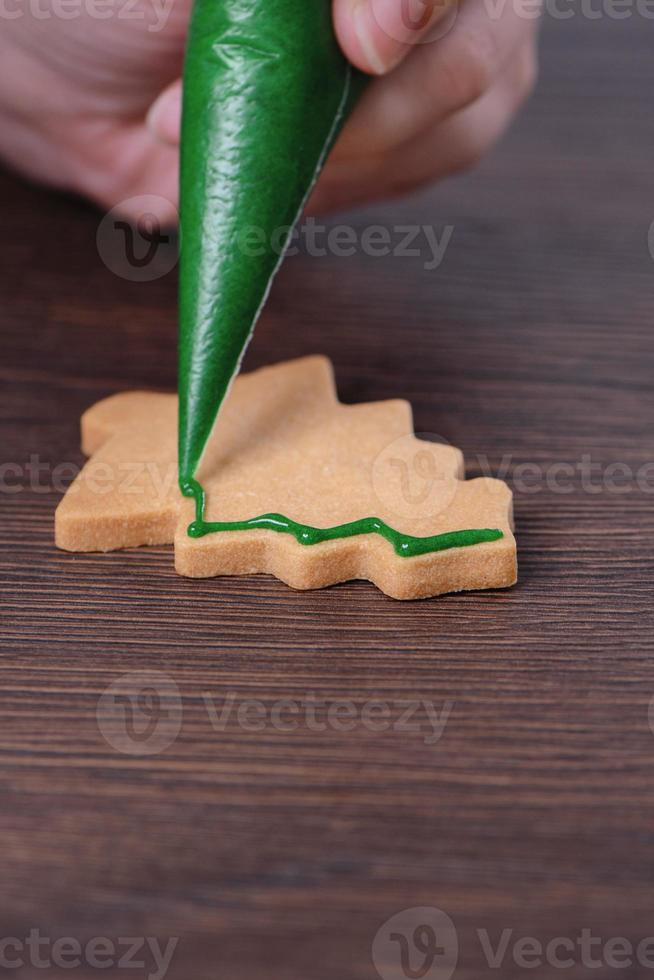 Close up of drawing Christmas tree sugar cookie on wooden table background with icing. photo