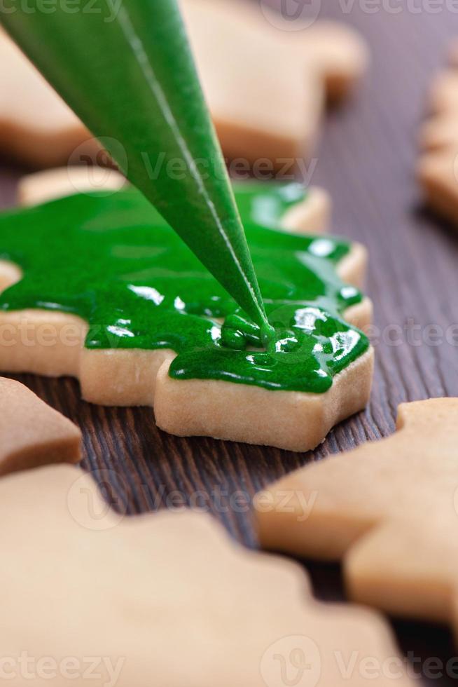 Close up of drawing Christmas tree sugar cookie on wooden table background with icing. photo