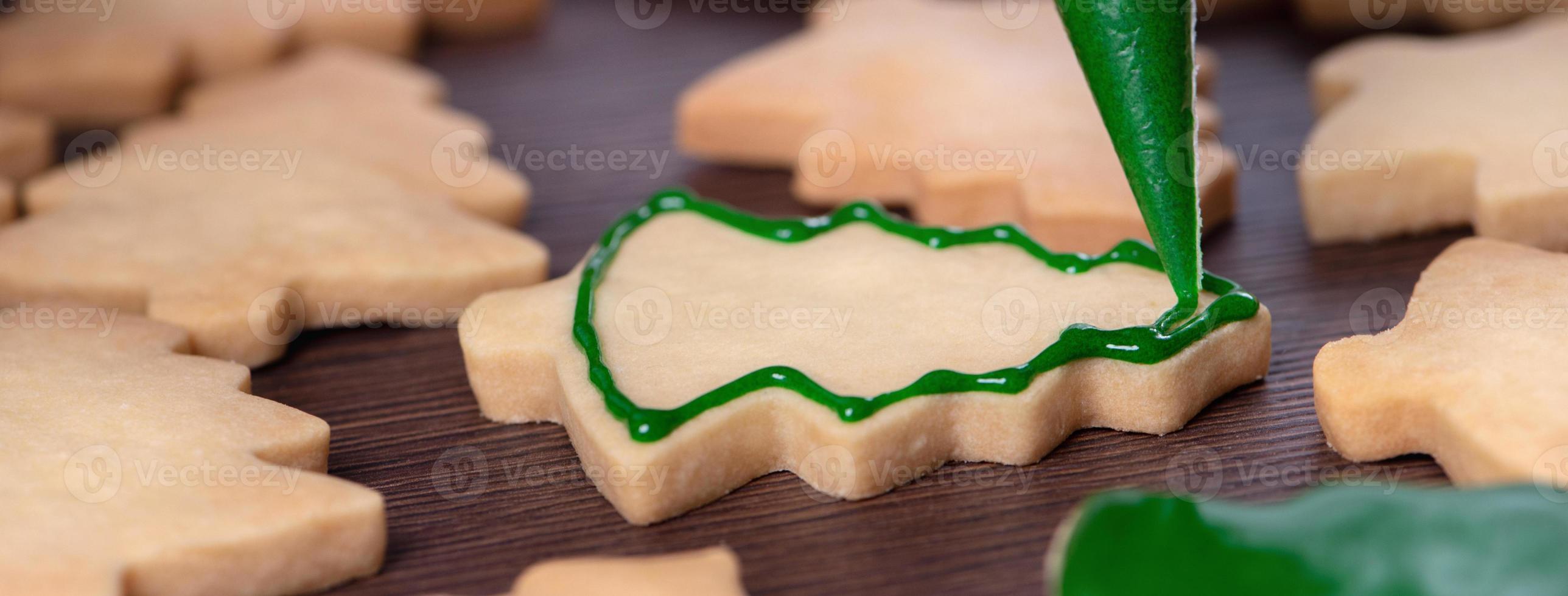 Close up of drawing Christmas tree sugar cookie on wooden table background with icing. photo