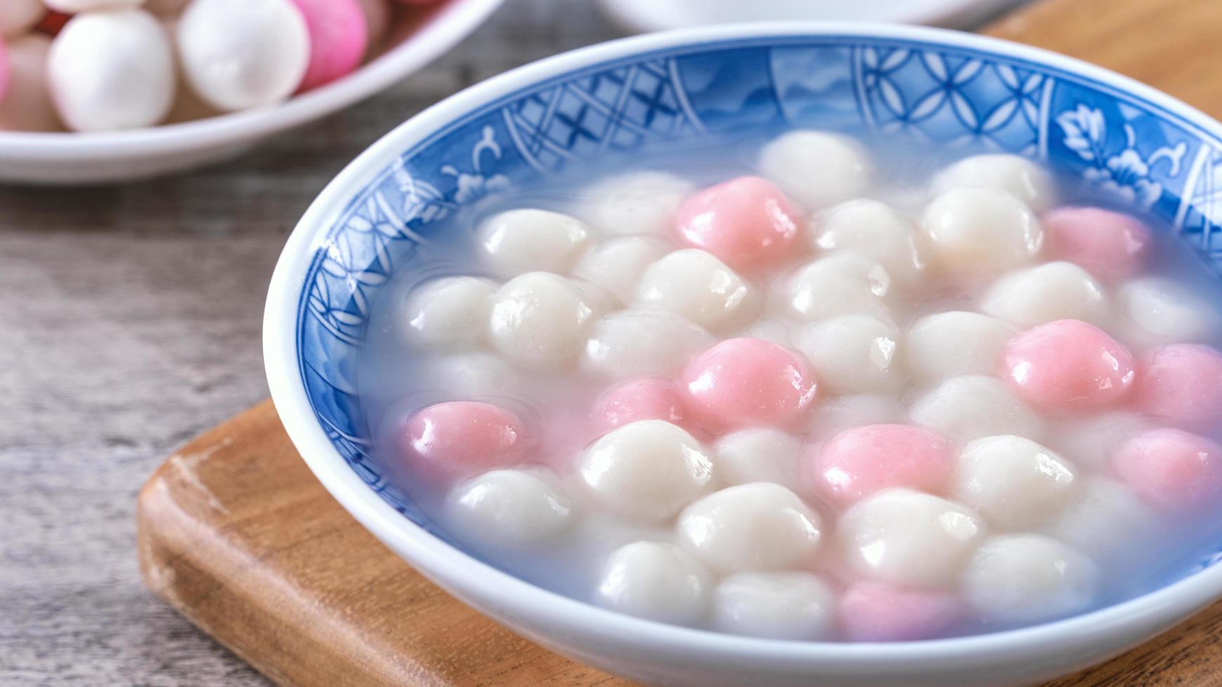 Close up of red and white tangyuan in blue bowl on wooden background for Winter solstice. photo