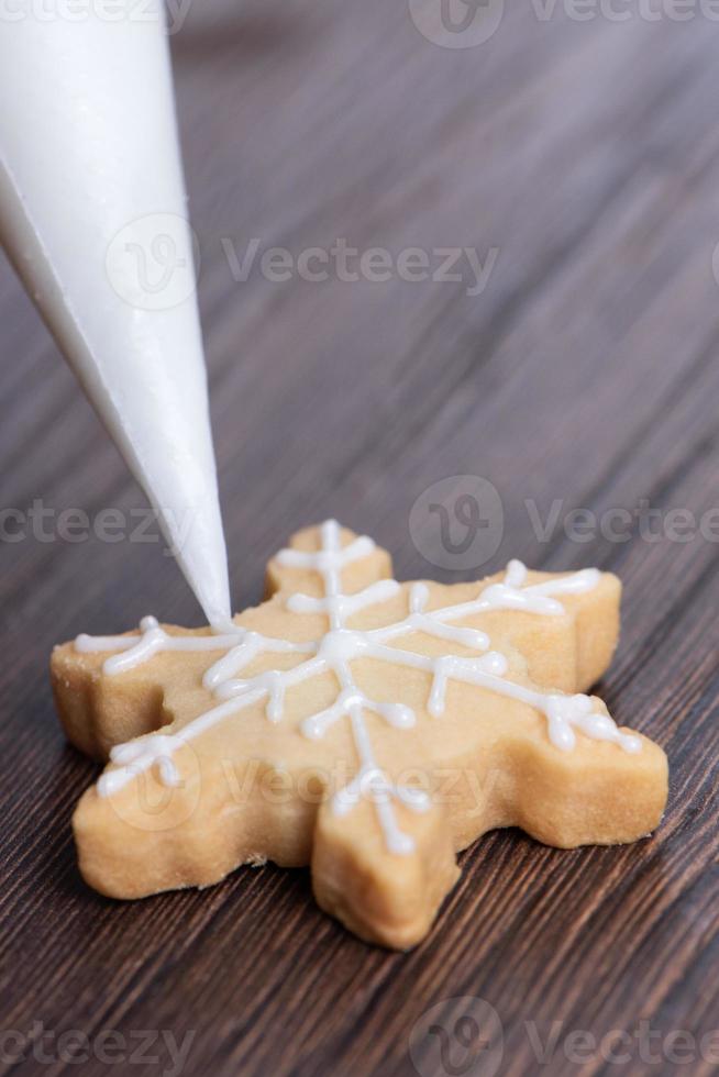 Close up of drawing Christmas snowflake sugar cookie on wooden table background with icing. photo