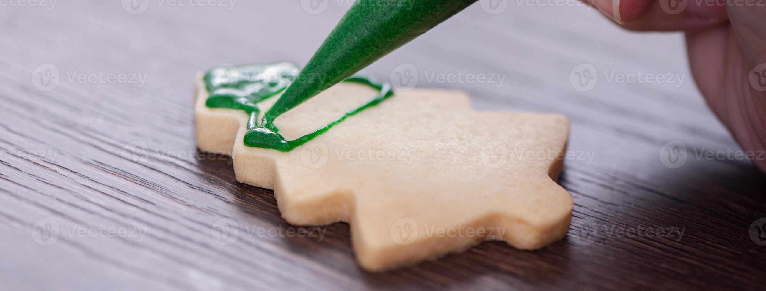 Close up of drawing Christmas tree sugar cookie on wooden table background with icing. photo