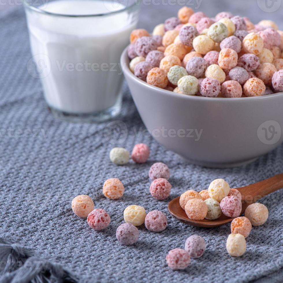 bolas de maíz de cereales de colores mezclan dulces en un bol sobre fondo de cemento gris. foto