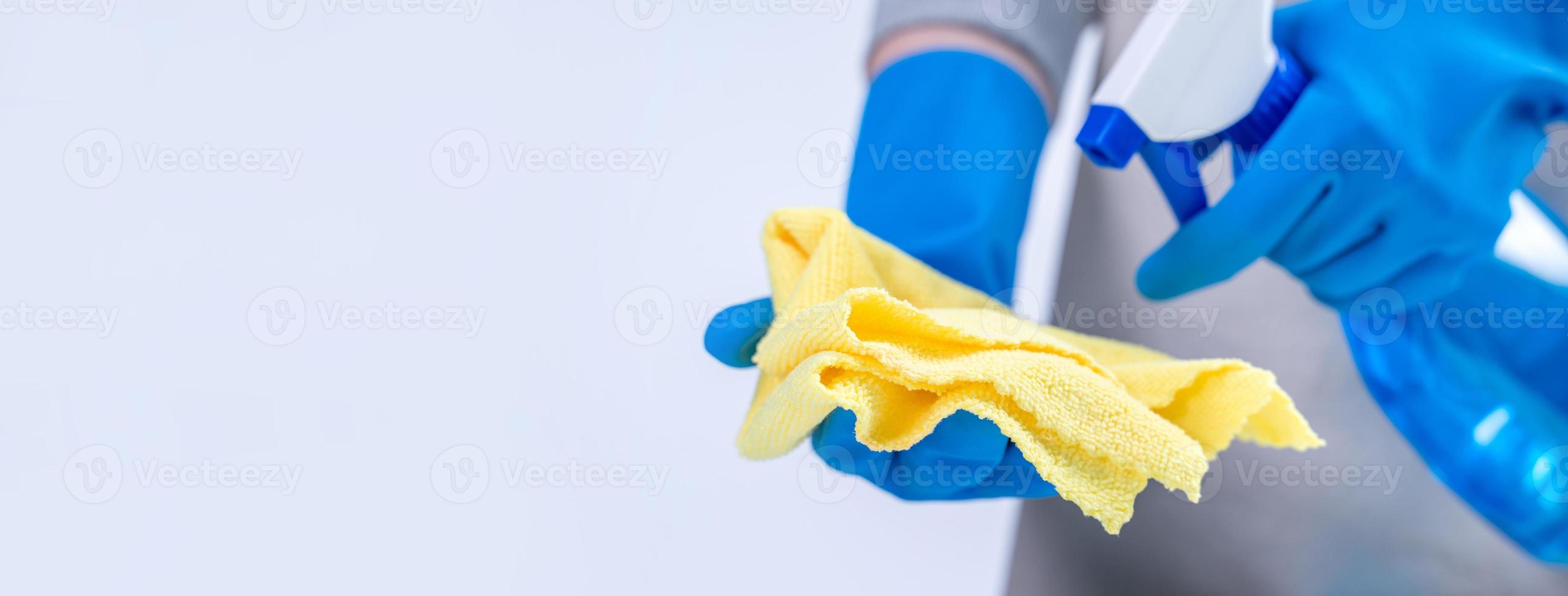 Woman housekeeper using rag and spraying bottle to clean the table surface. photo