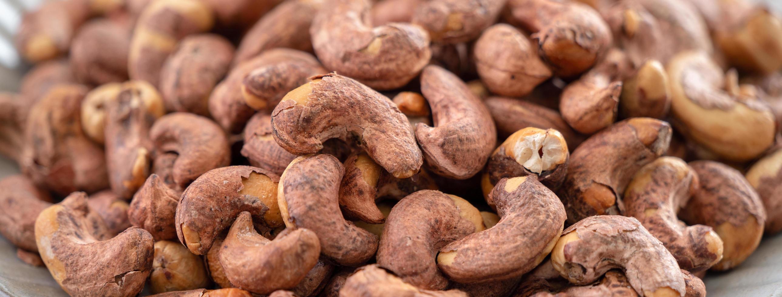 Cashew nuts with peel in a plate on wooden tray. photo