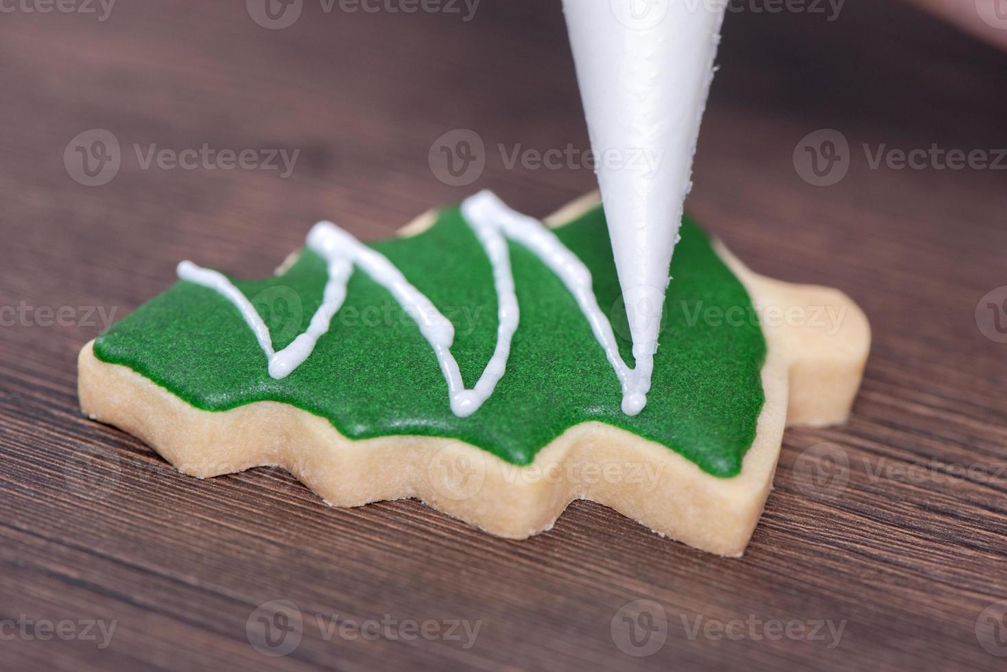 Close up of drawing Christmas tree sugar cookie on wooden table background with icing. photo