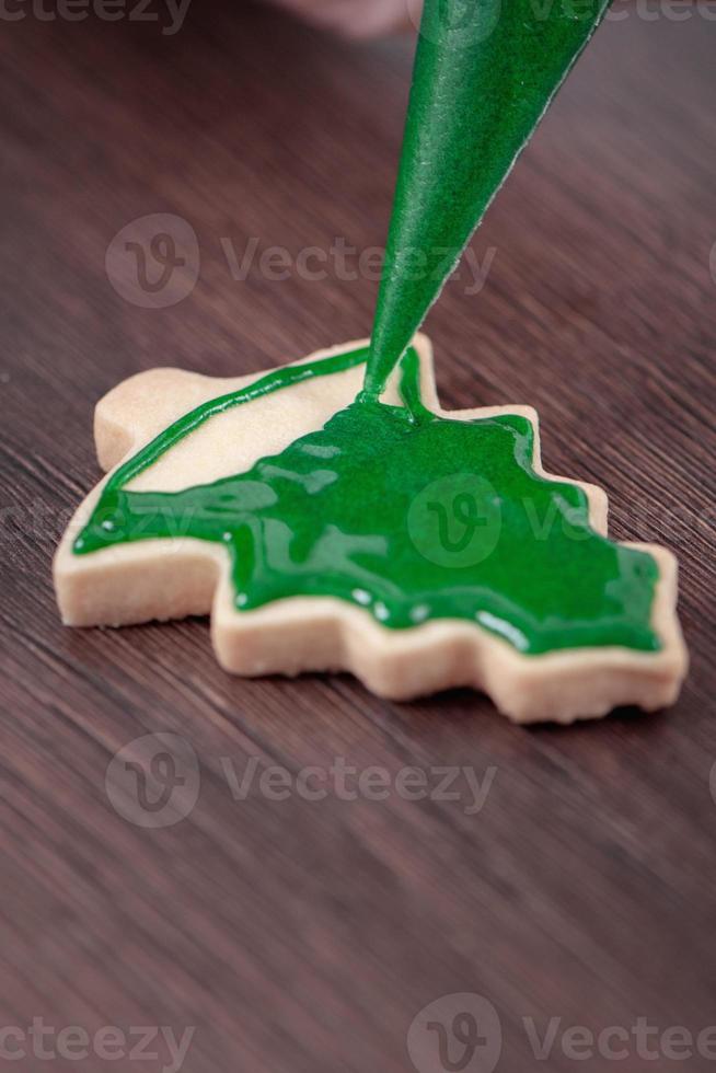 Close up of drawing Christmas tree sugar cookie on wooden table background with icing. photo