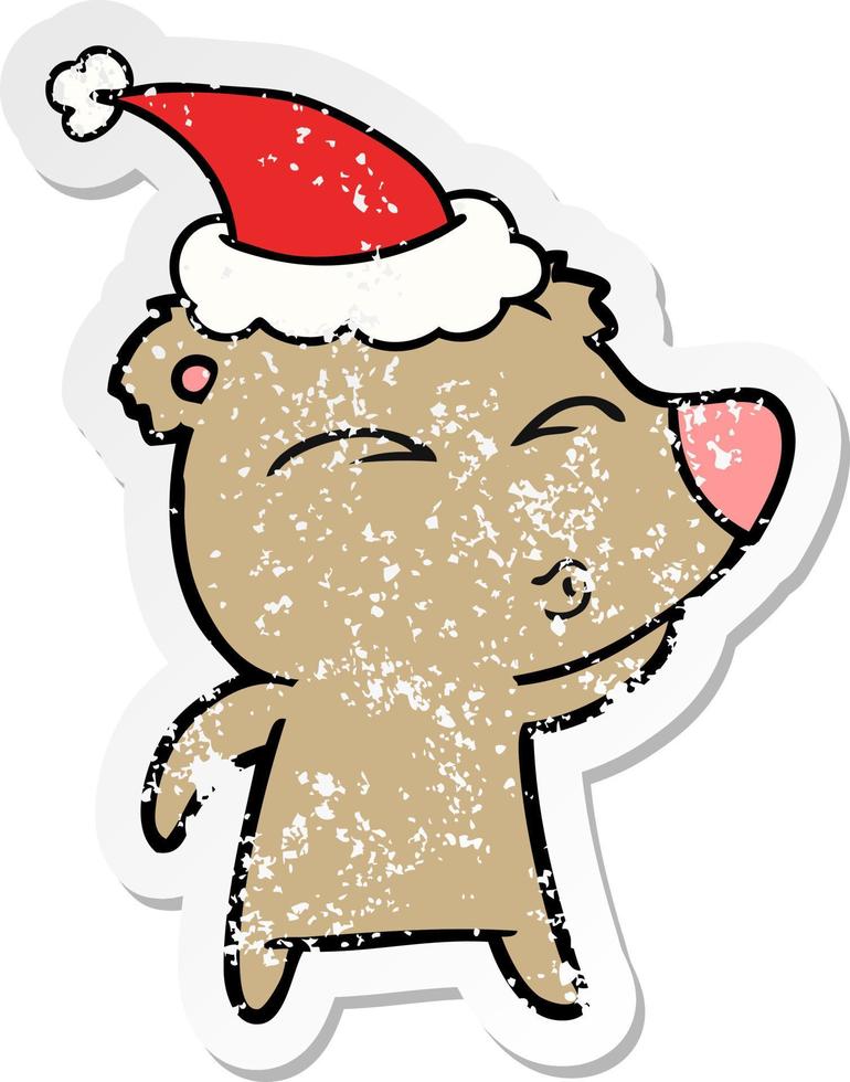 distressed sticker cartoon of a whistling bear wearing santa hat vector