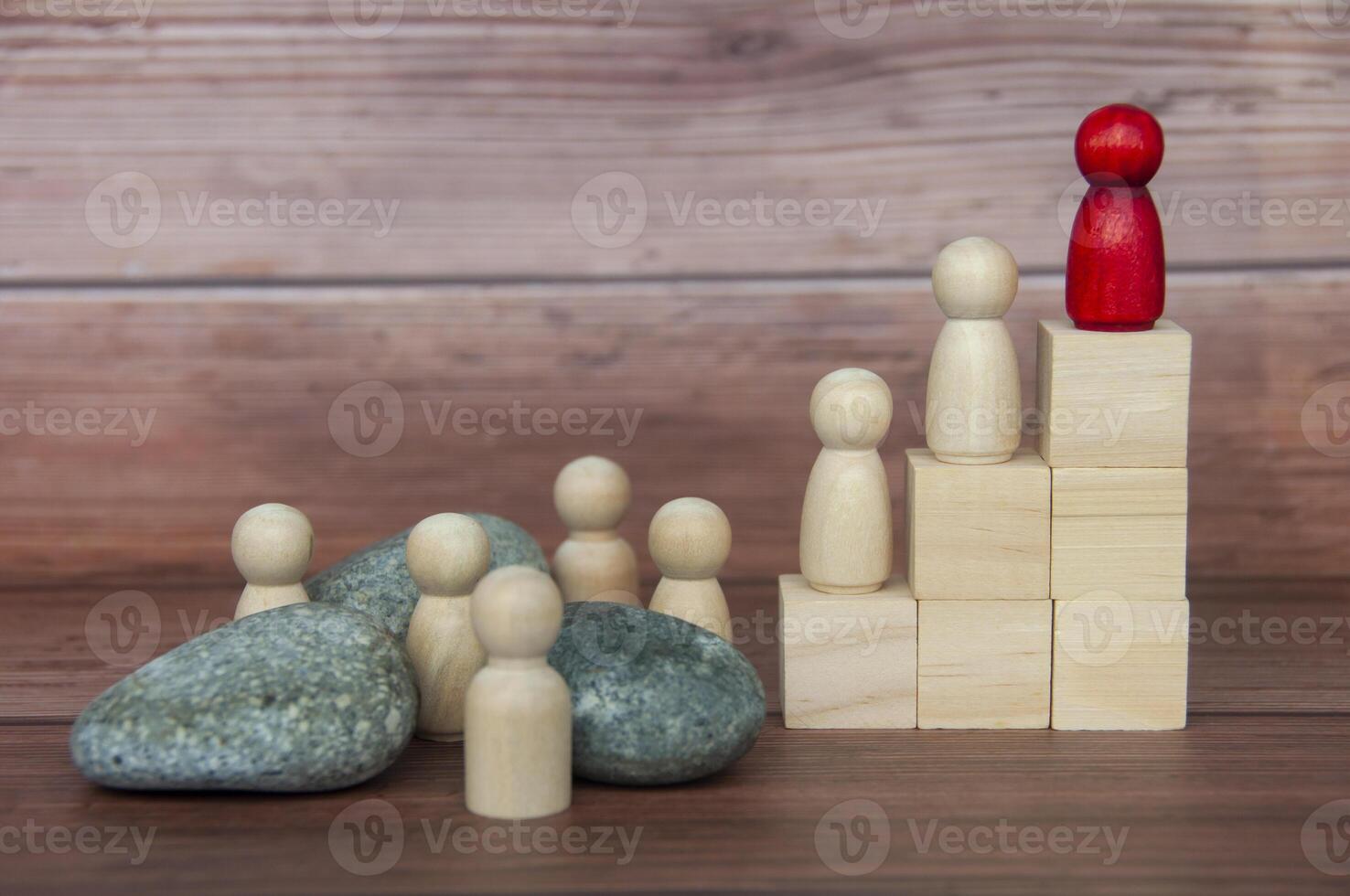 muñeca de madera roja encima de un bloque de madera con otros que tienen que enfrentar desafíos en el camino. foto