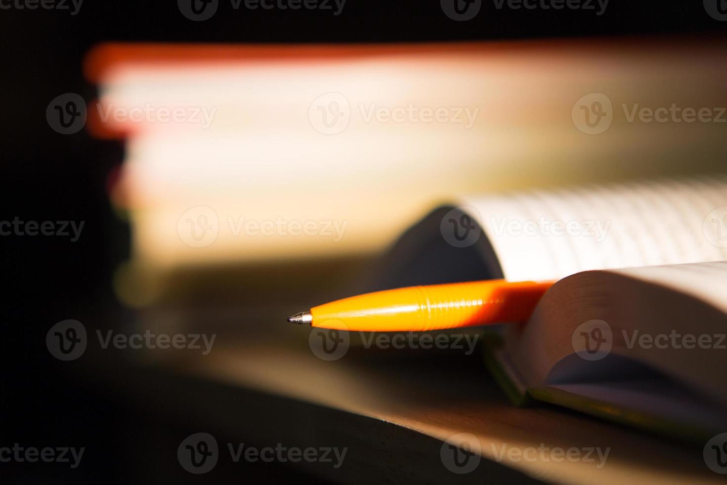 Close-up of a stack of books and a pen with paper for notes. The concept of home reading of paper books, education and school Institute, back to school, the library, making a synopsis. photo