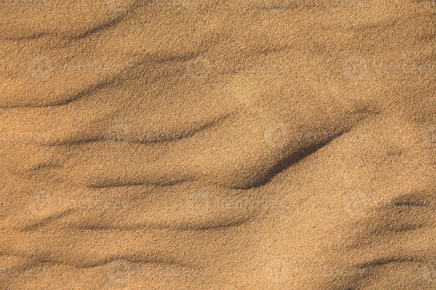 Texture of sand in the desert close-up background. A dune with a pattern of sand waves photo