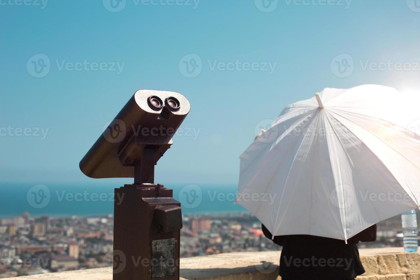 Binoculars from a height on the observation deck view of the panorama of the city and the sea. Sightseeing tour. photo