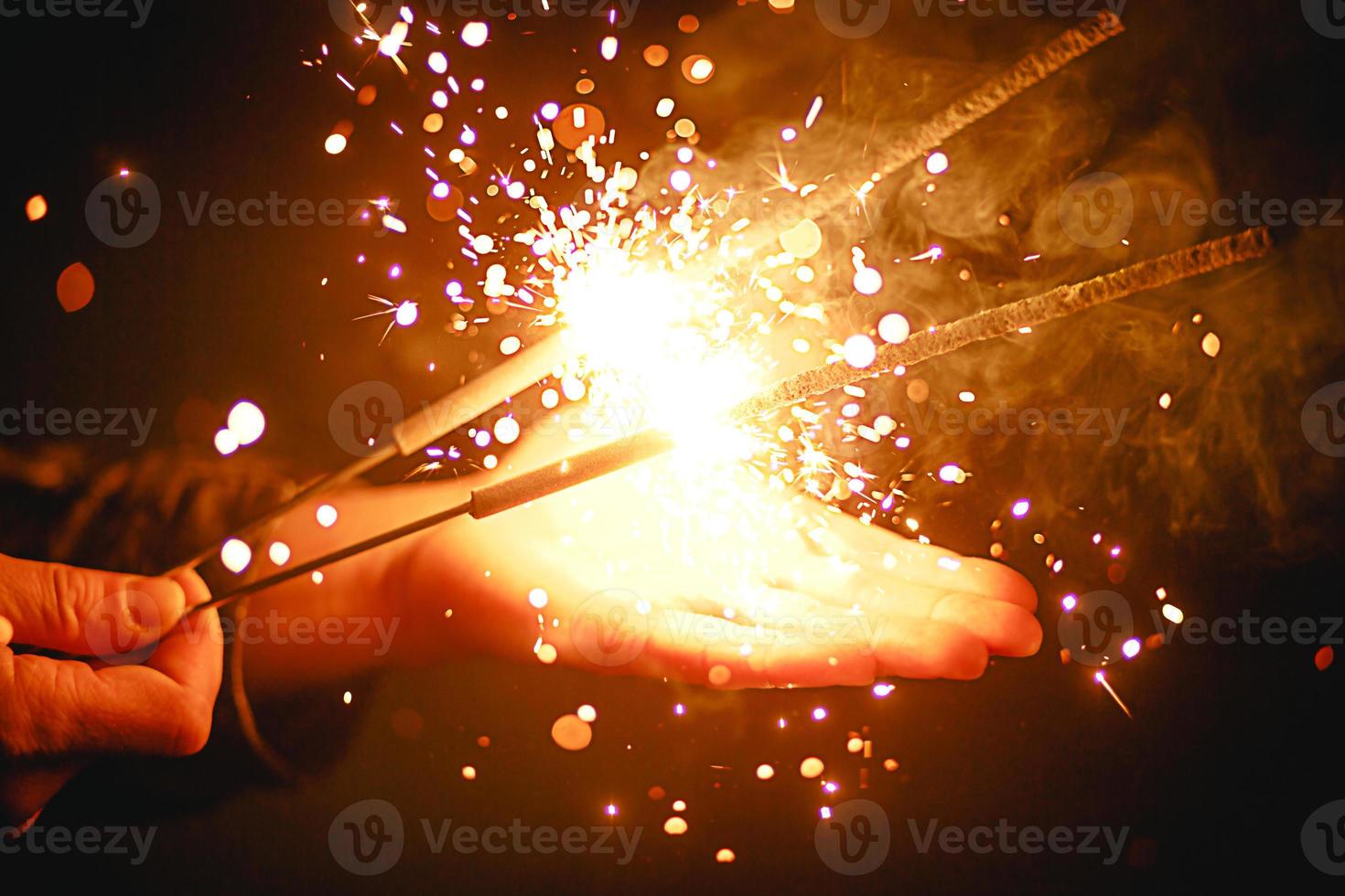 Sparks and light from sparklers in the dark on the palm of a person. Christmas magic, new year's eve, festive background. Space for text photo