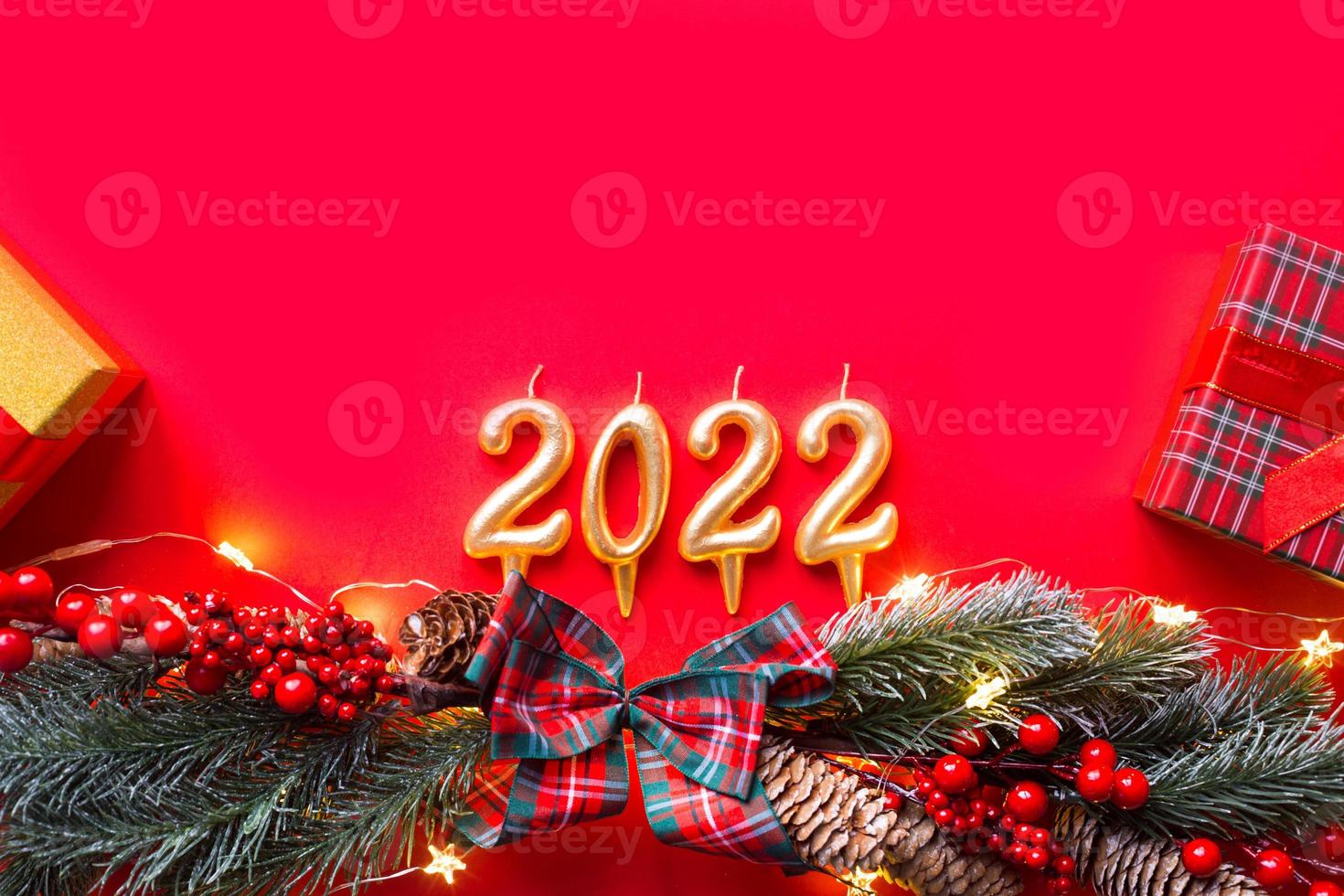 Happy New Year- golden candles numbers 2022 on a red background with Christmas tree, sequins, stars, glitter, gift boxes. Greetings, postcard. Calendar, cover. photo