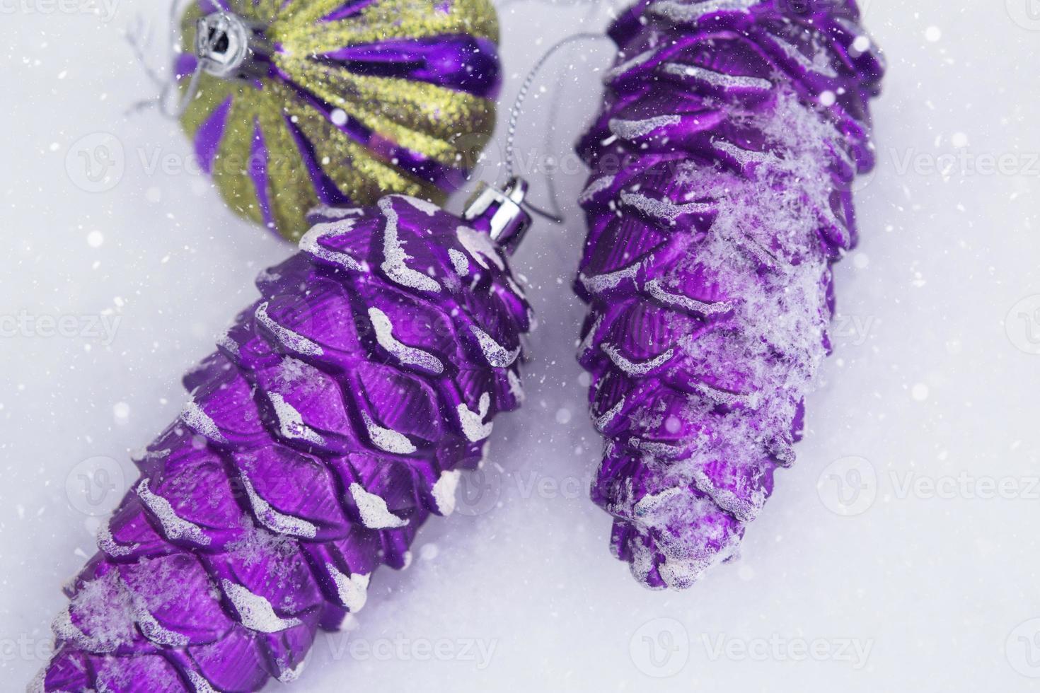 Purple Christmas tree toys in the shape of cones in the snow. A greeting card for the new year. Very peri panton 2022 color. Copy space photo