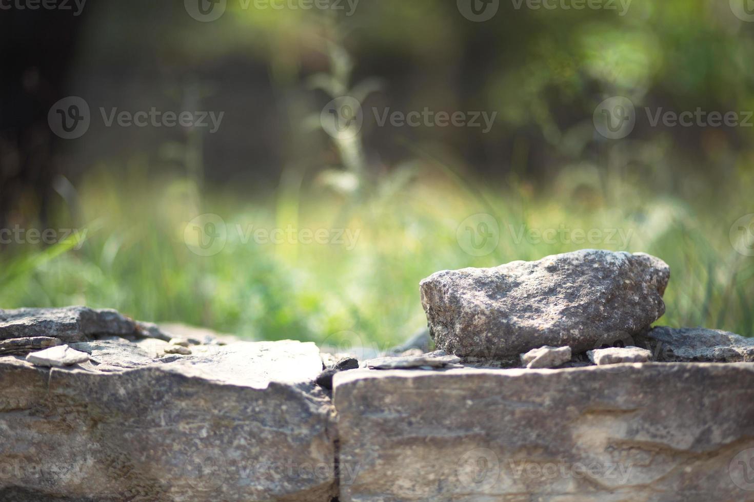 Masonry walls of natural sand color with green natural vegetation in the background in defocus.. Stone texture close-up foreground, ecology, eco-friendly theme photo