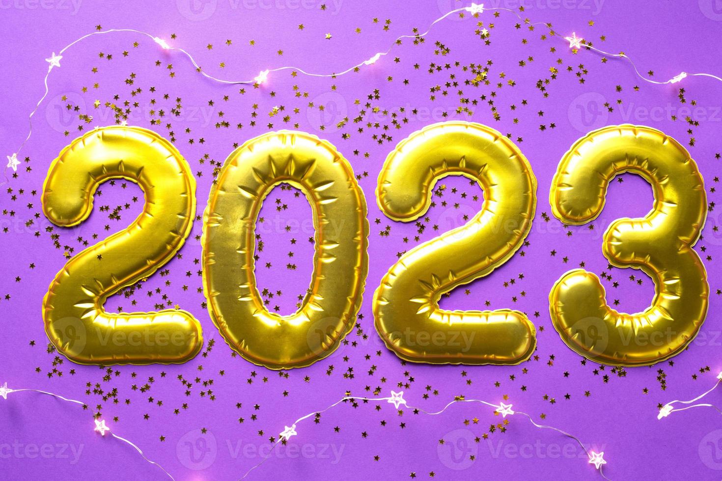 Happy New Year- golden numbers 2023 on a purple background with sequins, stars, glitter, lights of garlands. Greetings, postcard. Calendar, cover. photo