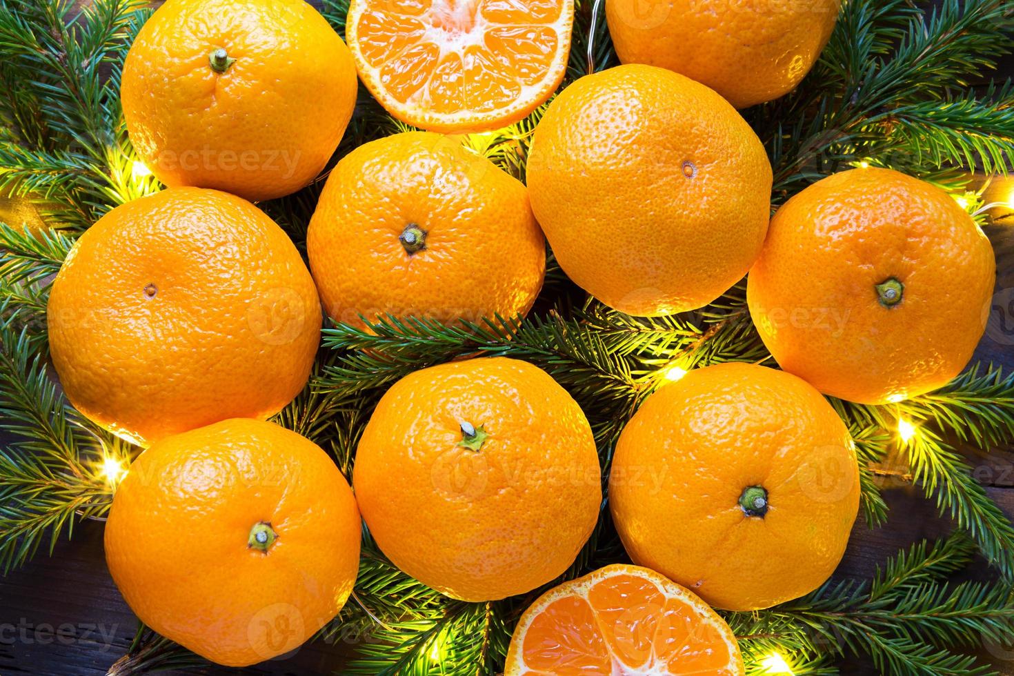 Fresh tangerines in garland lights, on fir branches and tinsel - new year's bright background. Half of an orange, citrus aroma of the holiday. Christmas, New year. Space for text. photo