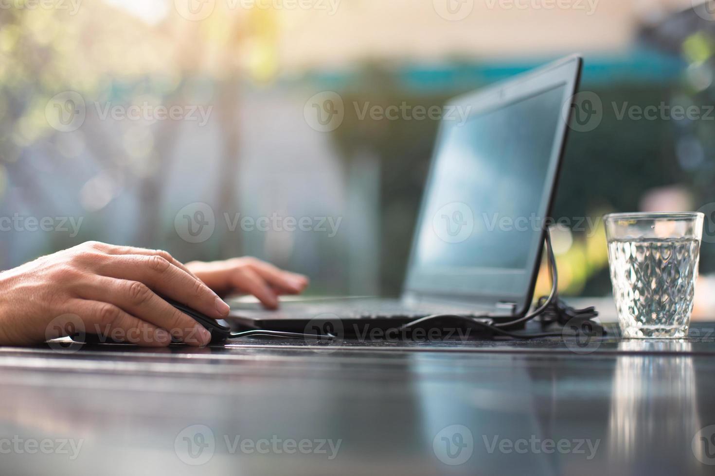 Working at a laptop in the outdoor courtyard - men's hands close-up. Home office, remote work, remote location. Using the keyboard and mouse, relax photo