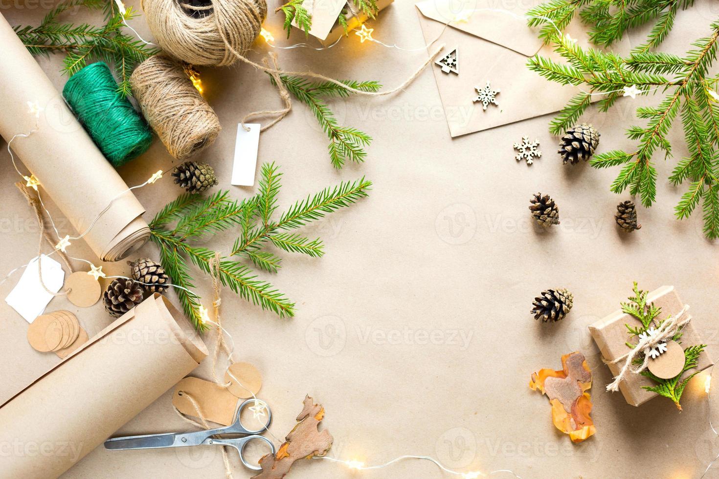 Background with copyspace for Christmas and new year in eco-friendly materials kraft paper, gift box, live fir branches, cones, twine. Tags with mock up, natural decor, hand made, DIY. Flatly photo