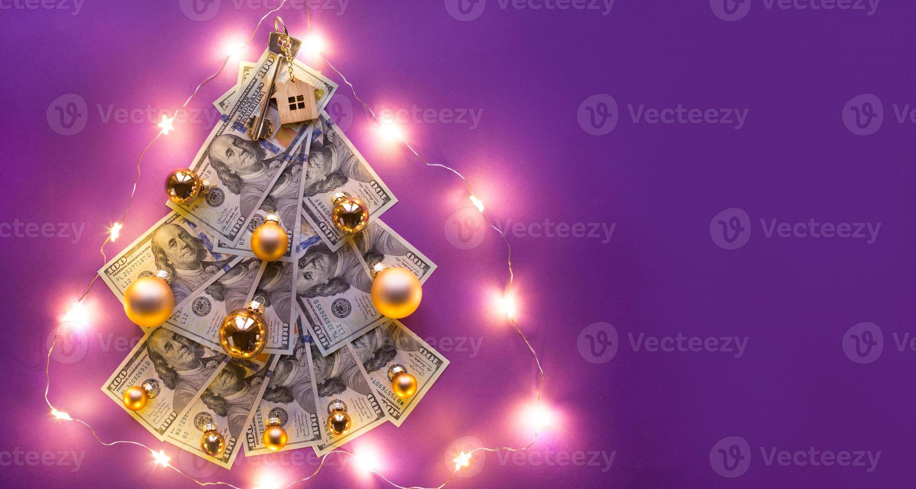 Christmas tree made of 100 dollar bills on purple background with copyspace and House key. Christmas decor of finance, savings, wealth, expenses in new year. Real estate, housing, mortgage, relocation photo