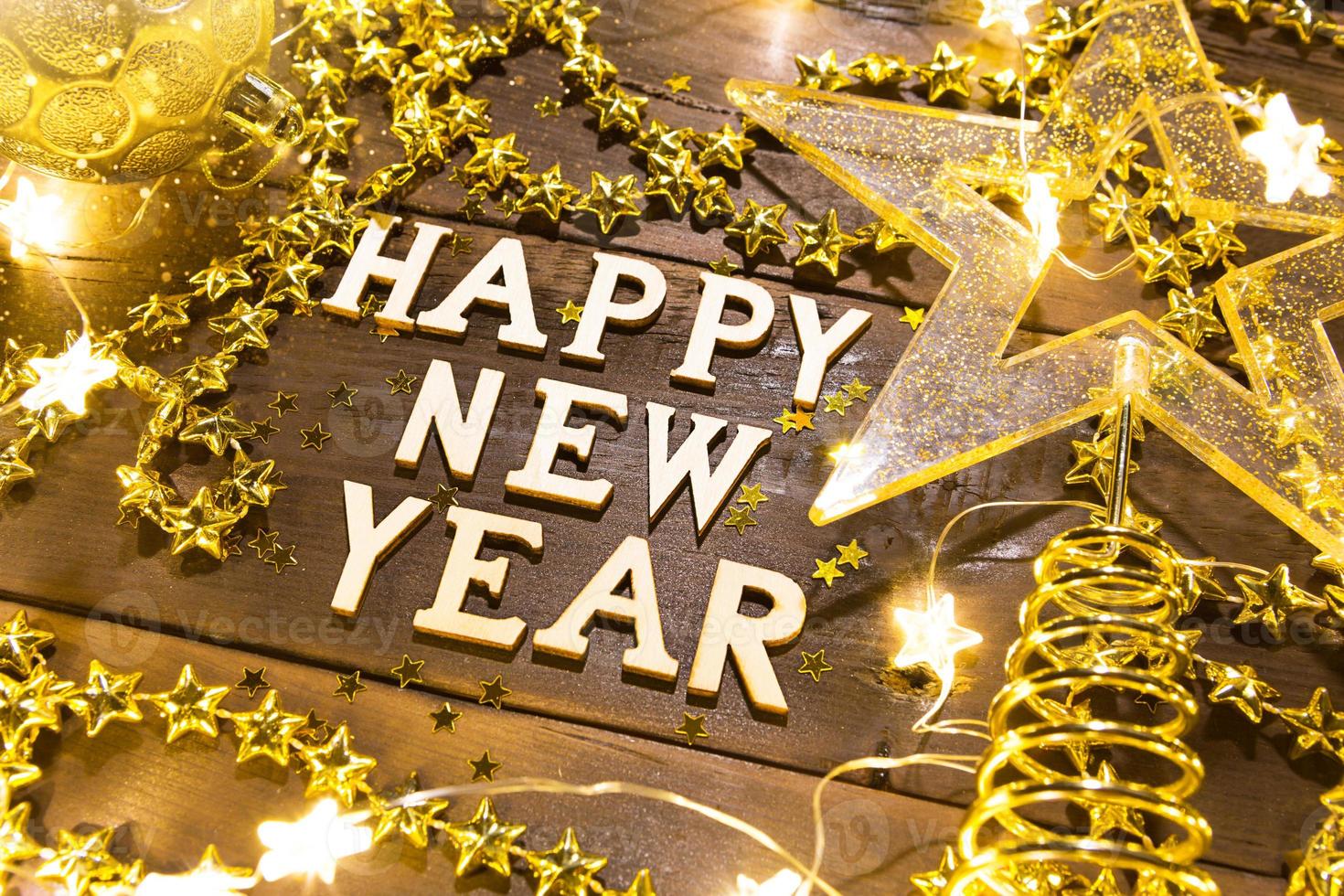 Happy New Year-wooden letters on a festive background with sequins, stars, lights of garlands. Greetings, postcard. photo