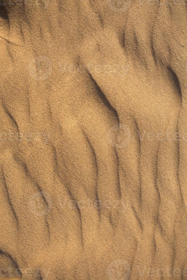 Texture of sand in the desert close-up background. A dune with a pattern of sand waves photo