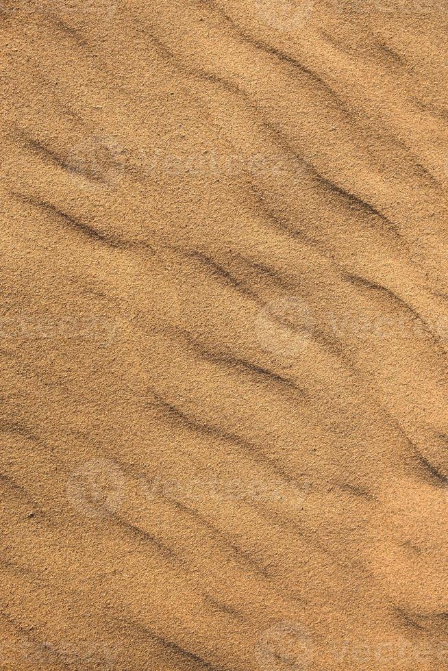 Texture of sand in the desert close-up background. A dune with a pattern of sand waves photo