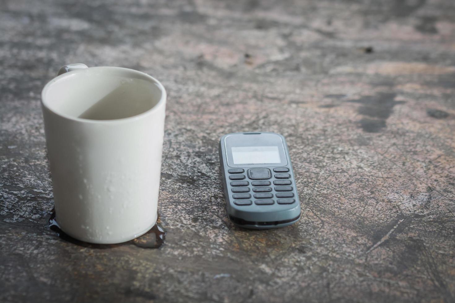 teléfono con taza en mesa de madera foto