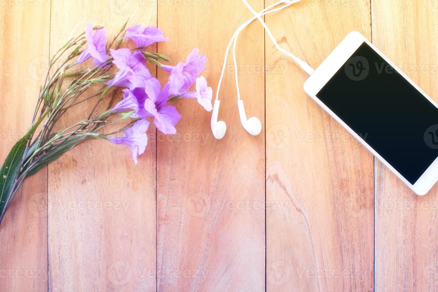 flower and smart phone on wooden table. top view. photo