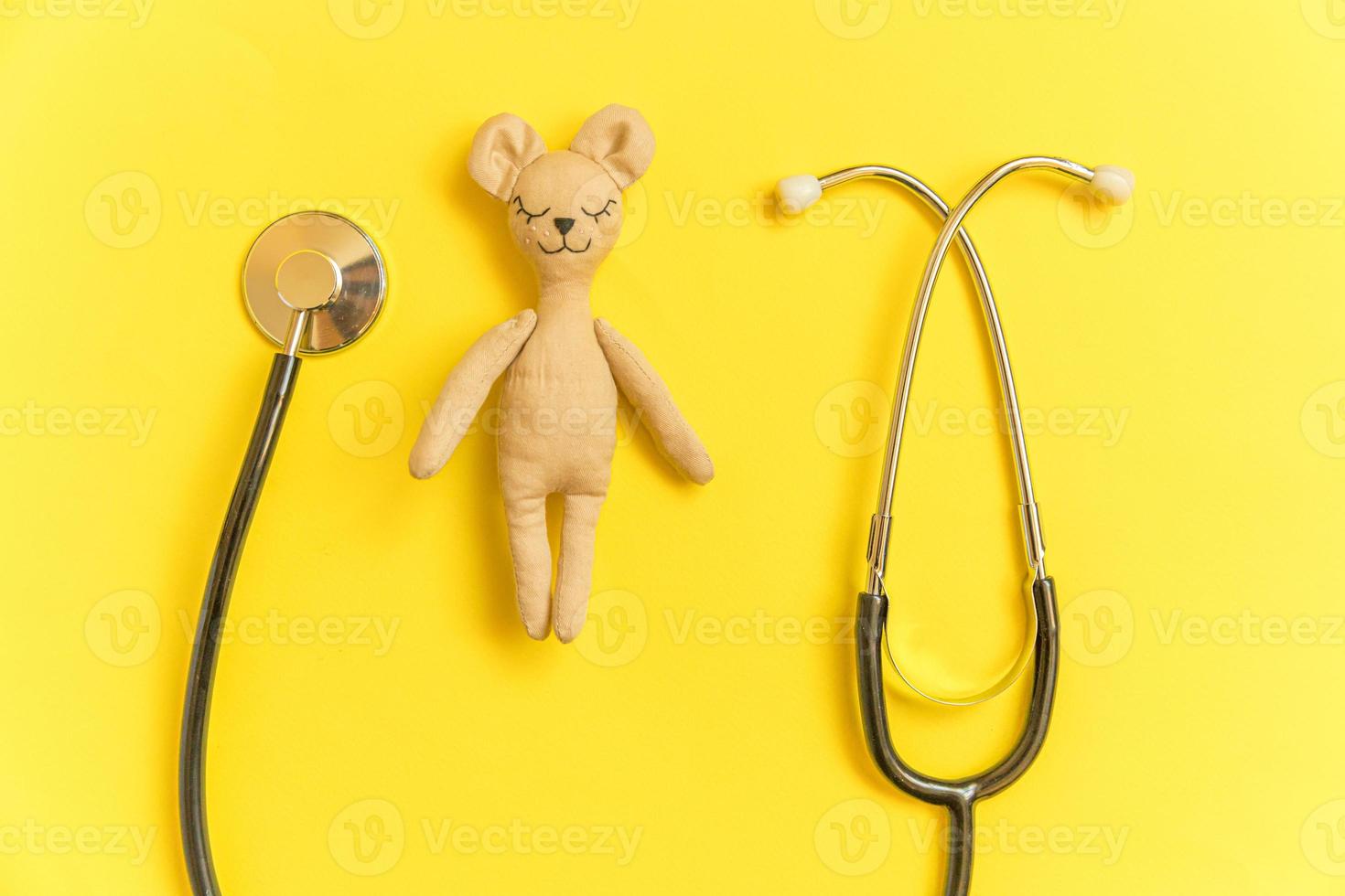 estetoscopio de equipo de medicina y oso de juguete de diseño simplemente mínimo aislado sobre fondo amarillo. concepto de médico de niños de atención médica. símbolo de pediatra. diseño de vista superior plana, espacio de copia foto