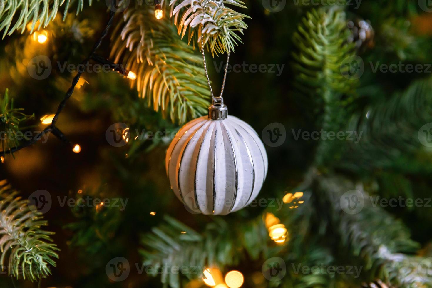 Classic Christmas decorated New year tree. Christmas tree with wite and silver decorations, ornaments toy and ball. Modern classical style interior design apartment. Christmas eve at home. photo